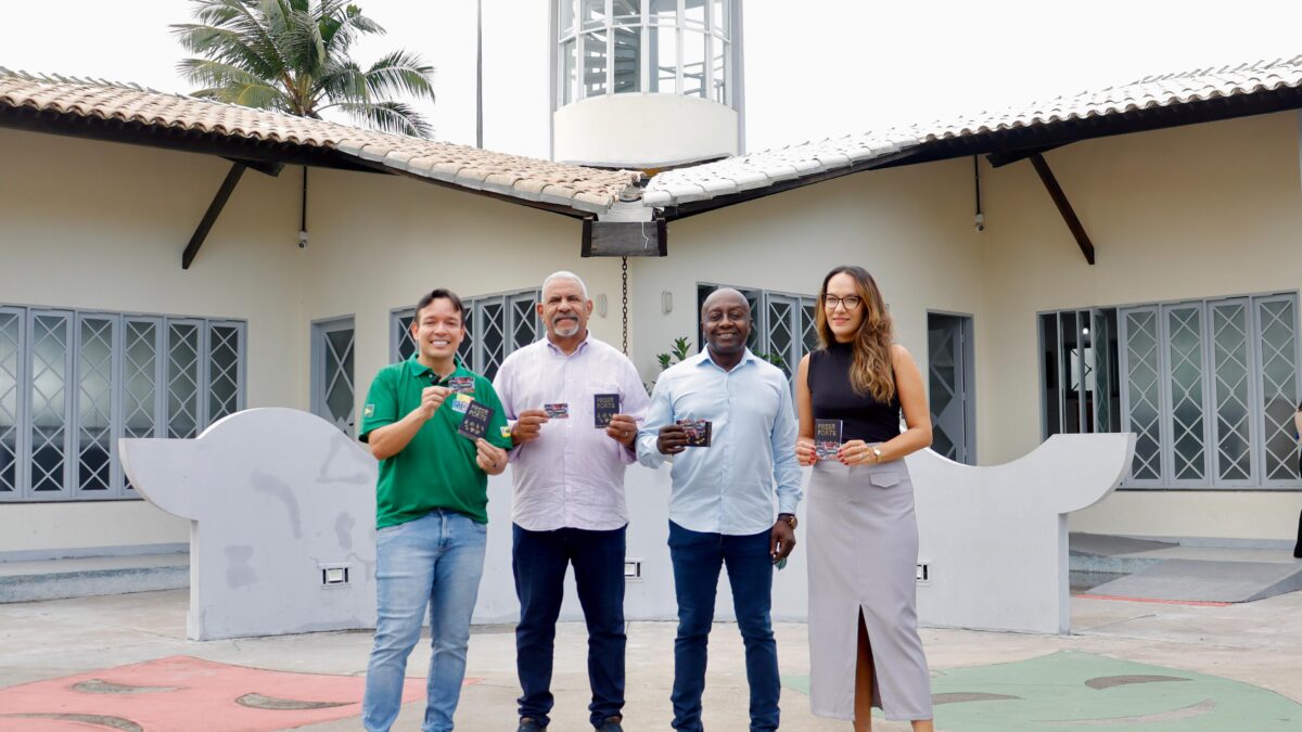 Quatro pessoas em pé, seguram o cartão Mais Aracaju Turista em frente ao Mirante da 13 de Julho