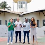 Quatro pessoas em pé, seguram o cartão Mais Aracaju Turista em frente ao Mirante da 13 de Julho